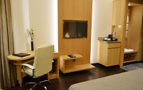 a hotel room with a chair and a desk and a television at The Umrao in New Delhi