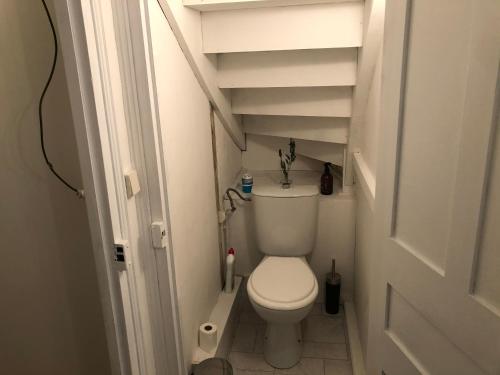 a small bathroom with a white toilet and stairs at Gîte des Lavandes in Oradour-Fanais