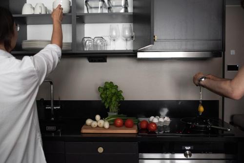 a man reaching for a shelf in a kitchen at Bob W Koti Katajanokka in Helsinki