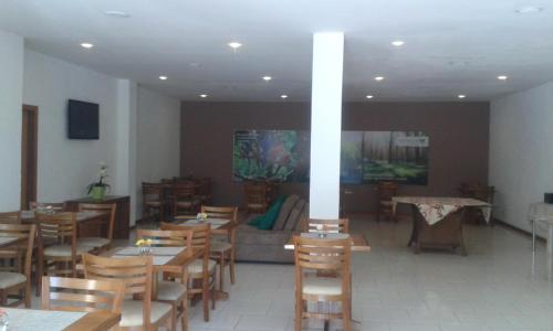 a restaurant with wooden tables and chairs and a couch at Pousada Matitaterê in Teresópolis