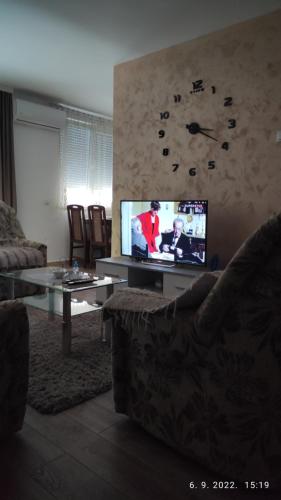a living room with a couch and a tv with a clock at Centar_park in Arandjelovac
