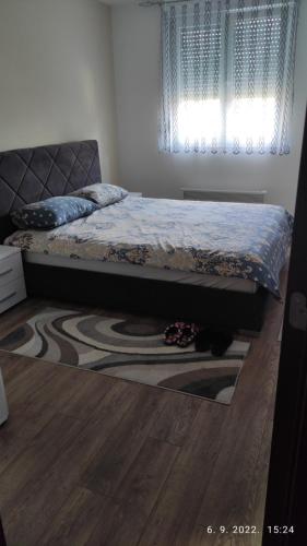 a bed in a bedroom with a rug and a window at Centar_park in Arandjelovac