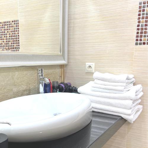 a bathroom with a white sink and a pile of towels at Cabo Negro, La Cassia 2 bedrooms appartment , shared pool , 150 m away from the Beach, and Golf course in Martil
