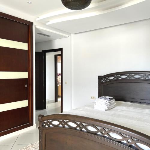 a bedroom with a wooden bed and a door at Cabo Negro, La Cassia 2 bedrooms appartment , shared pool , 150 m away from the Beach, and Golf course in Martil