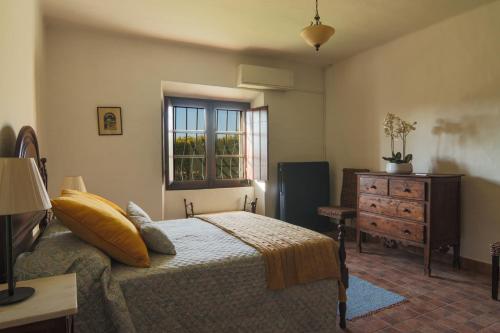 a bedroom with a bed and a dresser and a window at Monte Ribeira de Mures in Évora