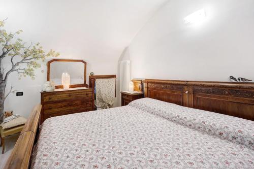 1 dormitorio con cama de madera y espejo en La casa tonda en Dolceacqua