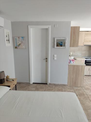 a white room with a door and a kitchen at Silvia's Apartments in Corfu Town