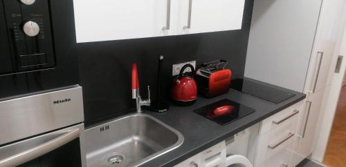 um balcão de cozinha com um lavatório e um aparelho vermelho em Apartment Jakubská 676 em Praga