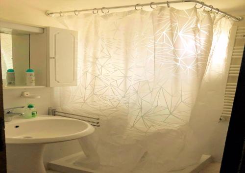 a bathroom with a white shower curtain and a sink at Un Piccolo Rifugio in San Potito