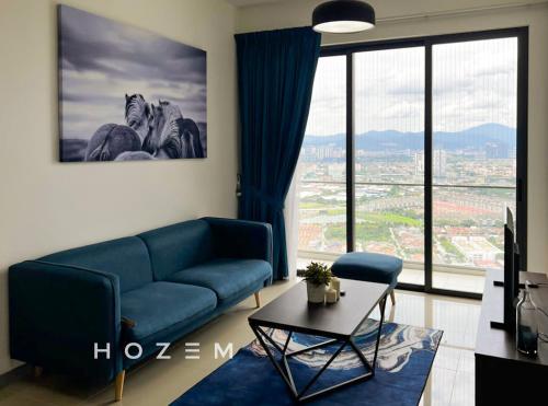 ein Wohnzimmer mit einem blauen Sofa und einem großen Fenster in der Unterkunft Cozy City View 4BR Near Desa Park / Mont Kiara in Kuala Lumpur