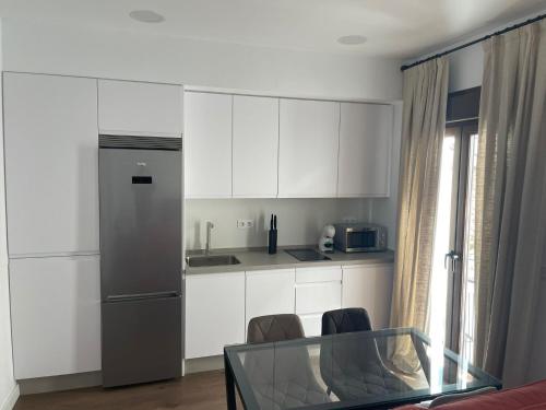 a kitchen with white cabinets and a glass table at Apartamentos Molinos in Constantina