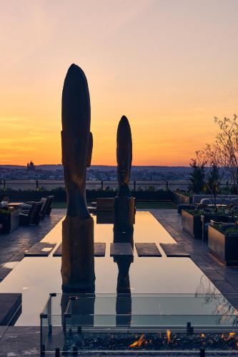 a statue on a patio with a sunset in the background at Equinox Hotel New York in New York