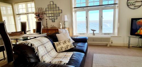 a living room with a blue couch and some windows at Shore Thing Beachfront Apartment Ramsgate - Sleeps 4 in Ramsgate