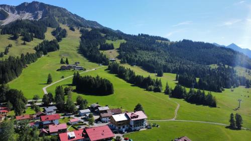 a small village on a green hill with trees at Bergzeit - Hotel & Appartements in Oberjoch