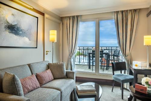 a living room with a couch and a large window at Hôtel Pont Royal Paris in Paris
