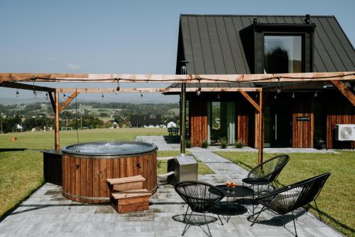 un patio con bañera de hidromasaje, mesa y sillas en oto.domki, en Rokiciny Podhalanskie