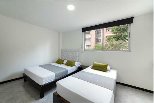 2 camas en una habitación con ventana en Hotel Casa Palermo, en Medellín