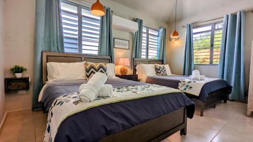 a bedroom with two beds with blue curtains and windows at Villas at Chalet De Buye in Cabo Rojo