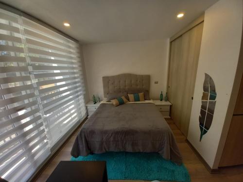a bedroom with a bed and a large window with blinds at Bello Departamento privado 2 personas,Pucon in Pucón