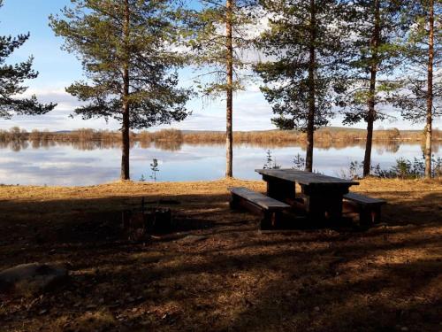 a picnic table and a bench in front of a lake at The Old Post Office in Hedenäset