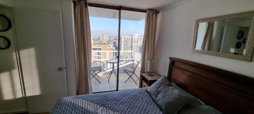 1 dormitorio con cama y vistas a un balcón en Amoblados San Isidro, en Santiago
