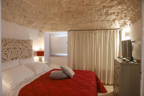 een slaapkamer met een bed met een rode deken bij TRULLI CALELLA by Apulia Hospitality in Locorotondo