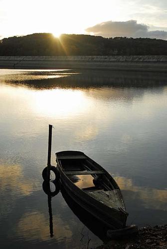 a boat sitting in the water with the sun setting at Maison Mon p’tit bonheur in Changey