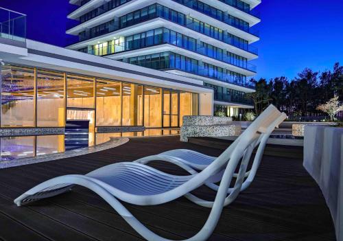 a white lounge chair on a deck in front of a building at Wave Międzyzdroje Resort & SPA in Międzyzdroje