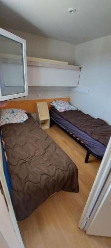 Cette chambre comprend 2 lits et une fenêtre sur le mur. dans l'établissement Mobil home au coeur de Brocéliande, à Paimpont