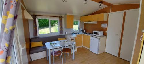 - une petite cuisine avec une petite table, une table et des chaises dans l'établissement Mobil home au coeur de Brocéliande, à Paimpont