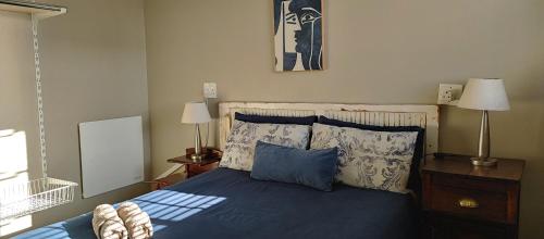 Schlafzimmer mit einem Bett mit blauer Bettwäsche und Kissen in der Unterkunft Happy Home - Woodstock in Kapstadt