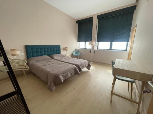 a bedroom with a bed with a blue headboard and two windows at Viña Femita in Villafranca del Bierzo