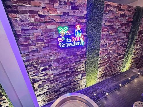 a bathroom with a sign on a brick wall at Vacay Spot experience Luna Sky! 65" TV BAR, BBQ, SHOWER massage jets, music, go to FL Keys in Homestead