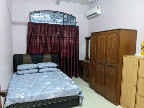 a bedroom with a bed and a dresser and a window at Aryani Homestay in Kampong Kelemak