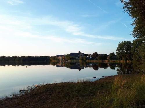 Vue sur un lac avec un bâtiment en arrière-plan dans l'établissement Mobil home au coeur de Brocéliande, à Paimpont