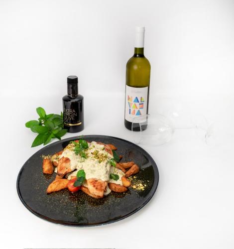 a plate of food on a table with a bottle of wine at Zepter Hotel Vrnjacka Banja, member of Zepter Hotels in Vrnjačka Banja
