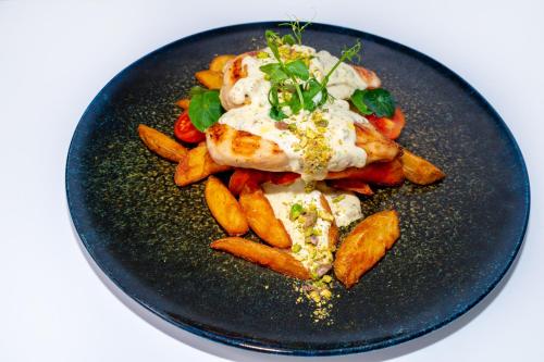 a black plate of food with chicken and vegetables at Zepter Hotel Vrnjacka Banja, member of Zepter Hotels in Vrnjačka Banja
