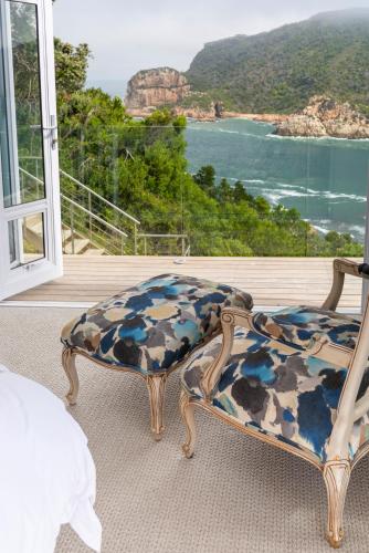 a bedroom with a couch and a view of the ocean at Infinity Villa in Knysna