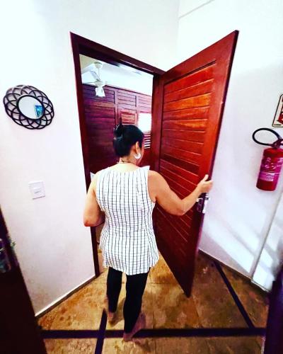 a woman opening a wooden door in a room at Residencial Bem-te-vi in Jericoacoara