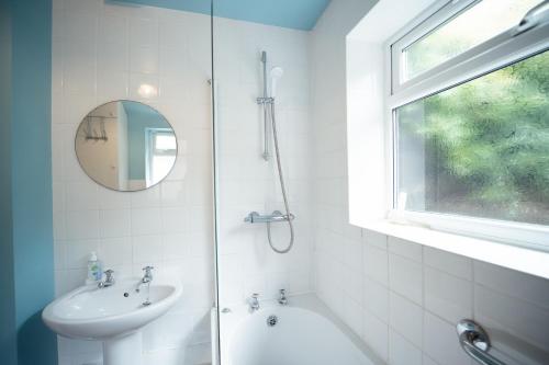 a bathroom with a shower and a sink and a mirror at Buckenham Cottage in Cromer