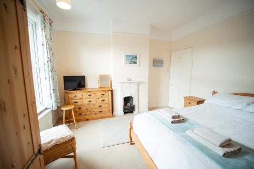 a bedroom with a bed and a tv and a fireplace at Buckenham Cottage in Cromer