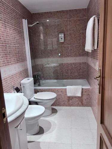 a bathroom with two toilets and a tub and a sink at Pleta 214 in Soldeu