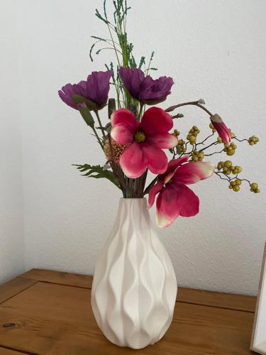 a white vase filled with pink flowers on a table at Unter dem Dach mit Parkplatz in Bremen
