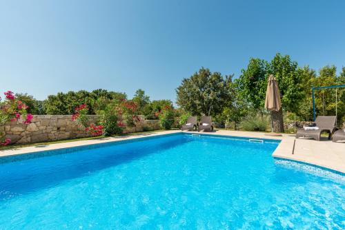 a swimming pool with chairs and an umbrella at Beautiful villa Natura with pool in Labin in Labin