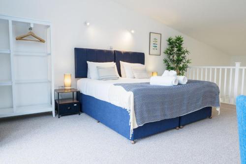 una camera da letto con un grande letto blu con cuscini bianchi di Helford a Mawnan
