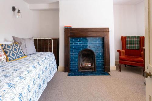 1 dormitorio con chimenea, 1 cama y 1 silla en Two Sides Cottage en Lymington