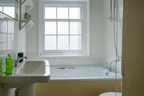 a bathroom with a sink and a tub and a window at Two Sides Cottage in Lymington