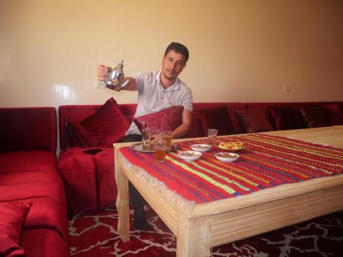 un hombre sentado en un sofá con una mesa en Maison D'hôtes Chez Bassou Agoudal en Agoudal