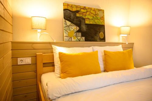 una camera da letto con un letto con cuscini gialli e 2 lampade di Space Apart Hotel a Luc'k