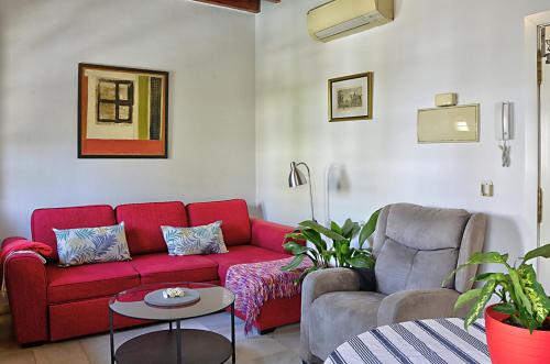 sala de estar con sofá rojo y silla en Balconies to the Orange Tree Square, en Sevilla